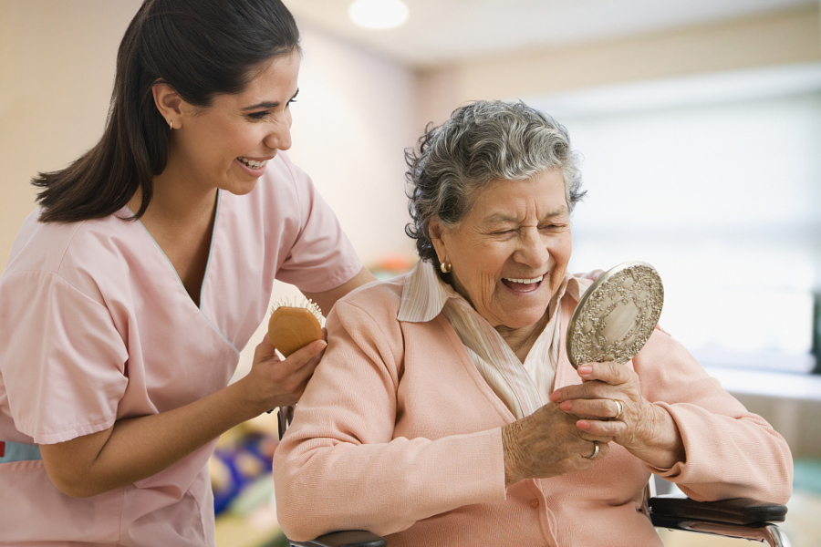 Hispanic nurse helping senior woman with hair